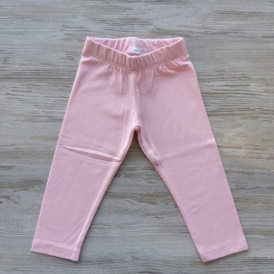 Leggings cor-de-rosa para criança sobre superfície de madeira clara