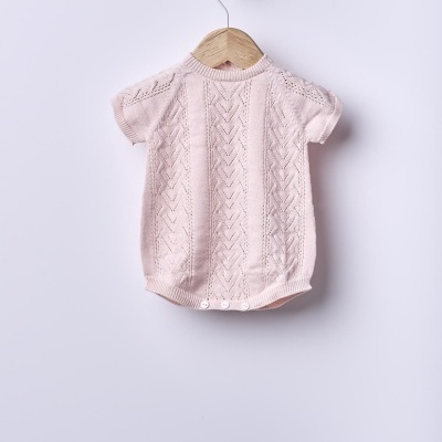 Body de bebé rosa claro em malha com padrão tricot, pendurado num cabide