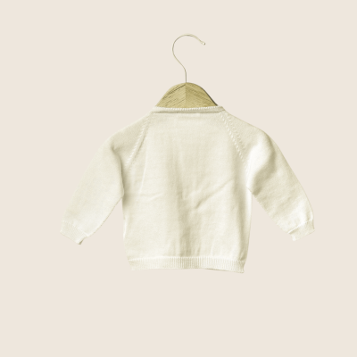 Camisola de malha branca para criança pendurada num cabide de madeira