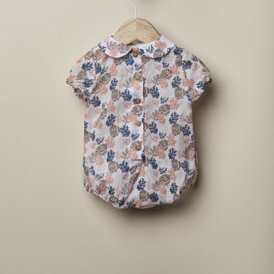 Body para bebé estampado com folhas e botões pendurado num cabide de madeira