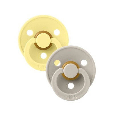 Duas chupetas de silicone amarelas e cinza com base redonda e texto BIBS