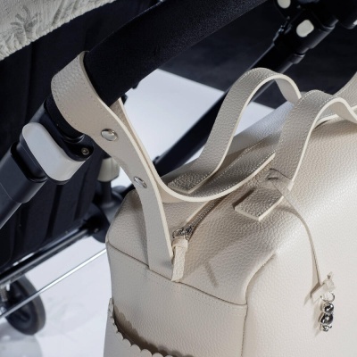 Mala bege de couro presa a carrinho preto por alças