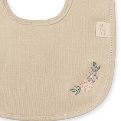 Babete bege com bordado floral e etiqueta com desenho de pássaro