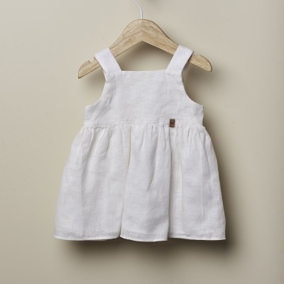 Vestido branco de bebé pendurado num cabide de madeira