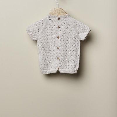 Casaco de malha creme com botões de madeira pendurado num cabide de madeira