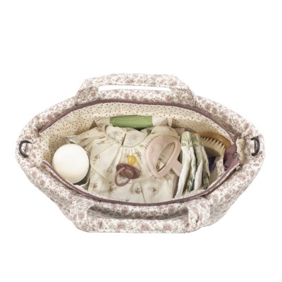 Bolsa com padrão floral castanho claro contendo itens para bebé, como chupetas, roupa, escova e panos.