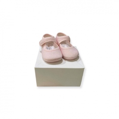 Sapatinhos de bebé rosa claro com fecho de velcro sobre uma caixa branca