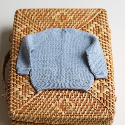 Pull de malha azul clara sobre caixa de vime trançado