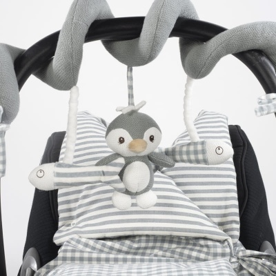 Brinquedo de pinguim cinza pendurado num carrinho de bebé com padrões riscado e às quadrículas cinza e branco