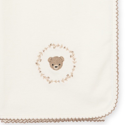 Pano branco com borda bege e bordado com o rosto de um urso castanho rodeado de flores.