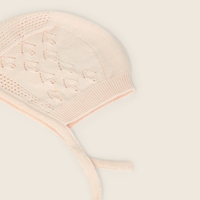Gorro em malha creme com padrão de pontos vazados e fitas para amarrar