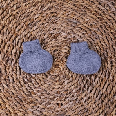 Peúgas para bebé cinza em malha sobre superfície de ráfia entrelaçada castanha