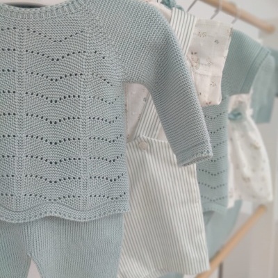 Conjunto de roupa de bebé azul claro em cabides brancos com logótipo de hipopótamo