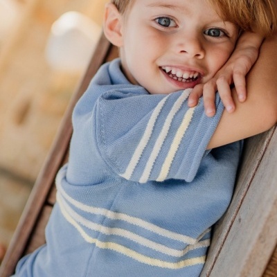 Camisola azul claro com riscas brancas e amarelas usada por criança sorridente