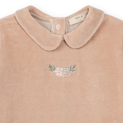 Detalhe de decote de roupa de bebé bege com etiqueta e bordado de flores
