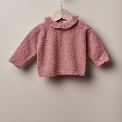 Camisola de bebé rosa pendurada numa cabide