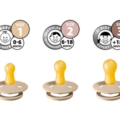 Três chupetas de silicone amarelo em bases redondas bege com indicações de tamanhos para diferentes idades.