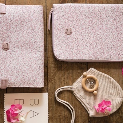 Bolsas de tecido floral rosa e saco de malha com argola de madeira em fundo de madeira