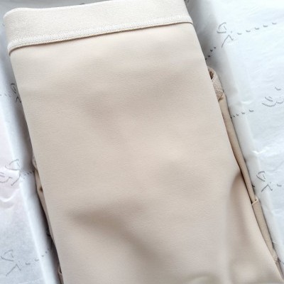 Calça bege claro com cintura elástica branca sobre papel de seda branco