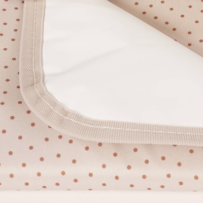 Toalha ou manta bege com pontos castanhos e borda branca