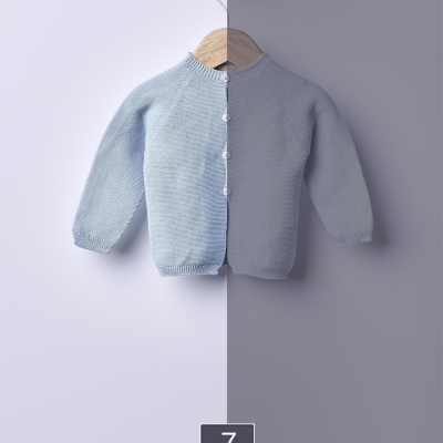 Camisola de malha azul claro para criança pendurada num cabide de madeira