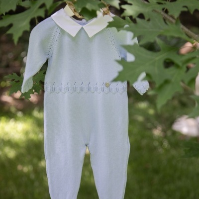 Macacão de bebé azul claro com gola branca pendurado numa árvore