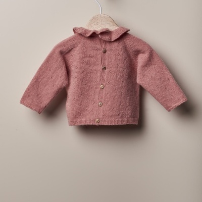 Camisola de malha cor de rosa com botões e gola folho pendurada num cabide