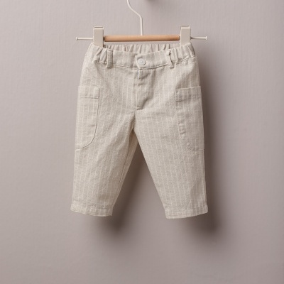 Calças de criança bege com riscas finas penduradas num cabide de madeira