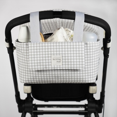 Bolsa cinzenta de xadrez pendurada na parte traseira de um carrinho de bebé com etiquetas