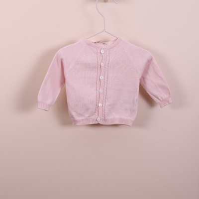 Casaco de malha rosa para bebé pendurado num cabide branco