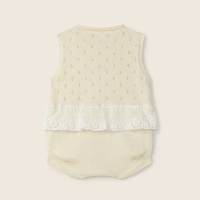 Body de bebé em malha creme com renda branca e padrão decorativo.