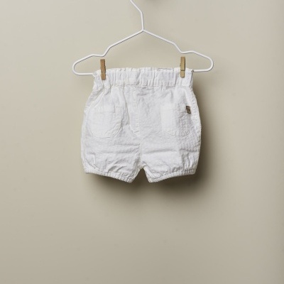 Calções brancos para bebé pendurados num cabide branco