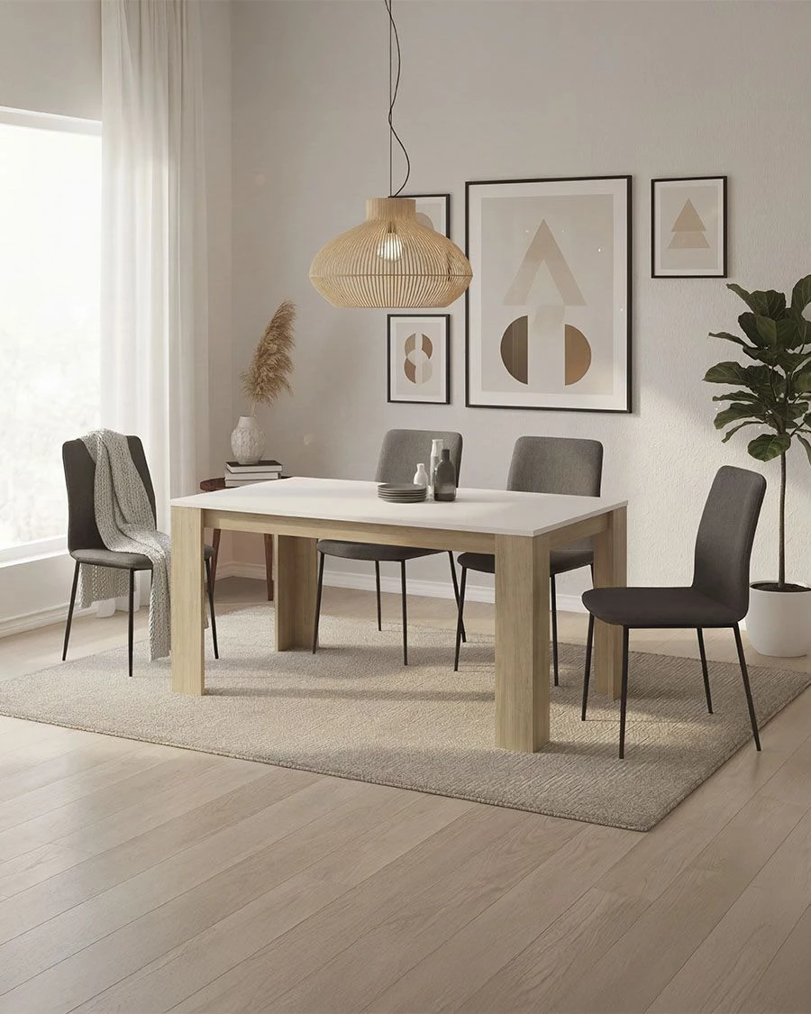 Sala de jantar com mesa branca de madeira clara, cadeiras cinzentas e candeeiro de rattan