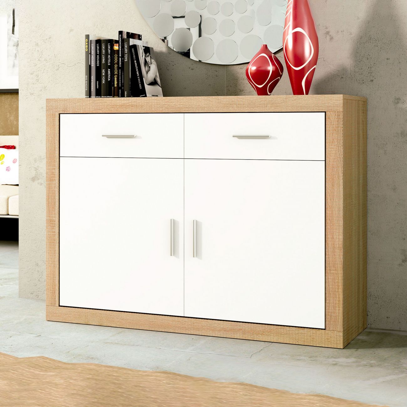 Móvel de arrumação em madeira clara com portas brancas e decoração em livro, espelho e vasos vermelhos