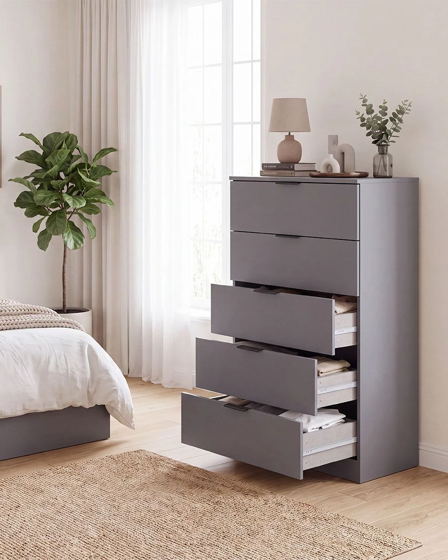 Cômoda cinza com gavetas abertas e decoração de quarto clara e natural