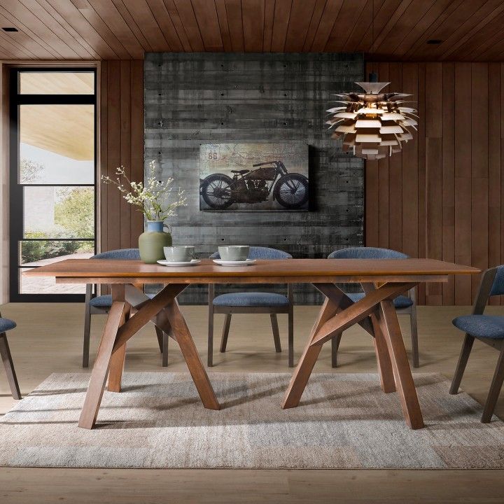 Mesa de jantar em madeira com cadeiras azuis e quadro de motocicleta na parede