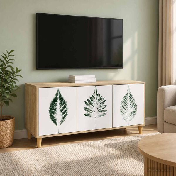 Móvel baixo de madeira clara com portas decoradas por folhas verdes numa sala com televisão, planta, sofá e cortinas