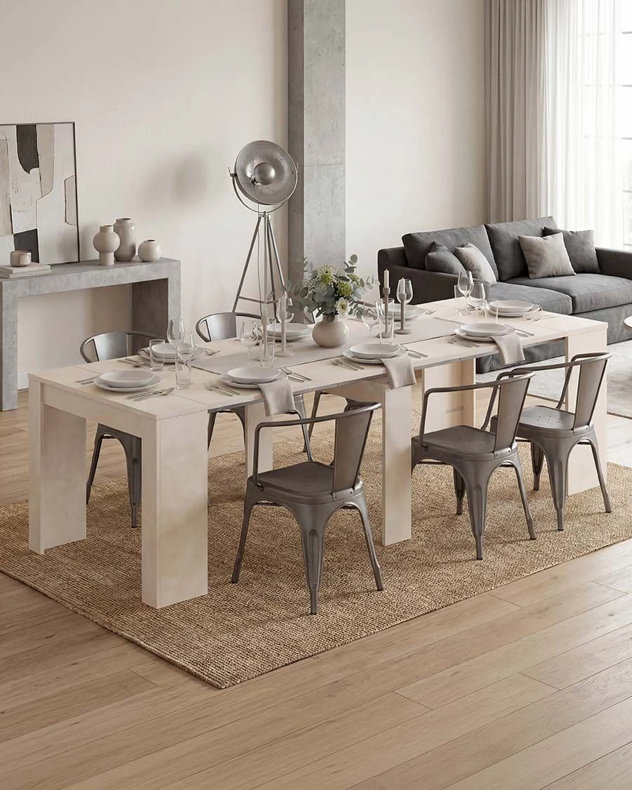 Mesa de jantar branca com cadeiras metálicas cinza e decoração, em sala com sofá cinza e tapete bege