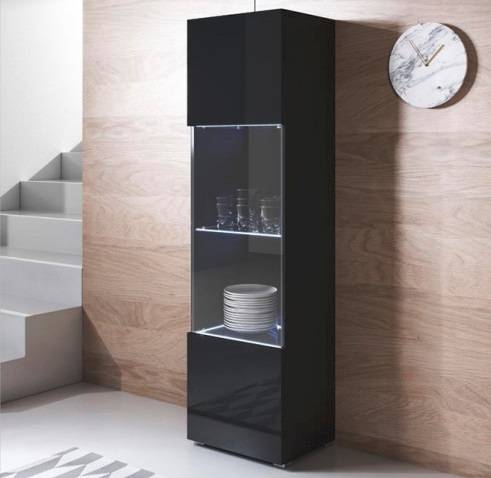 Móvel alto preto com porta de vidro contendo pratos e copos numa sala com parede de madeira e escada cinzenta