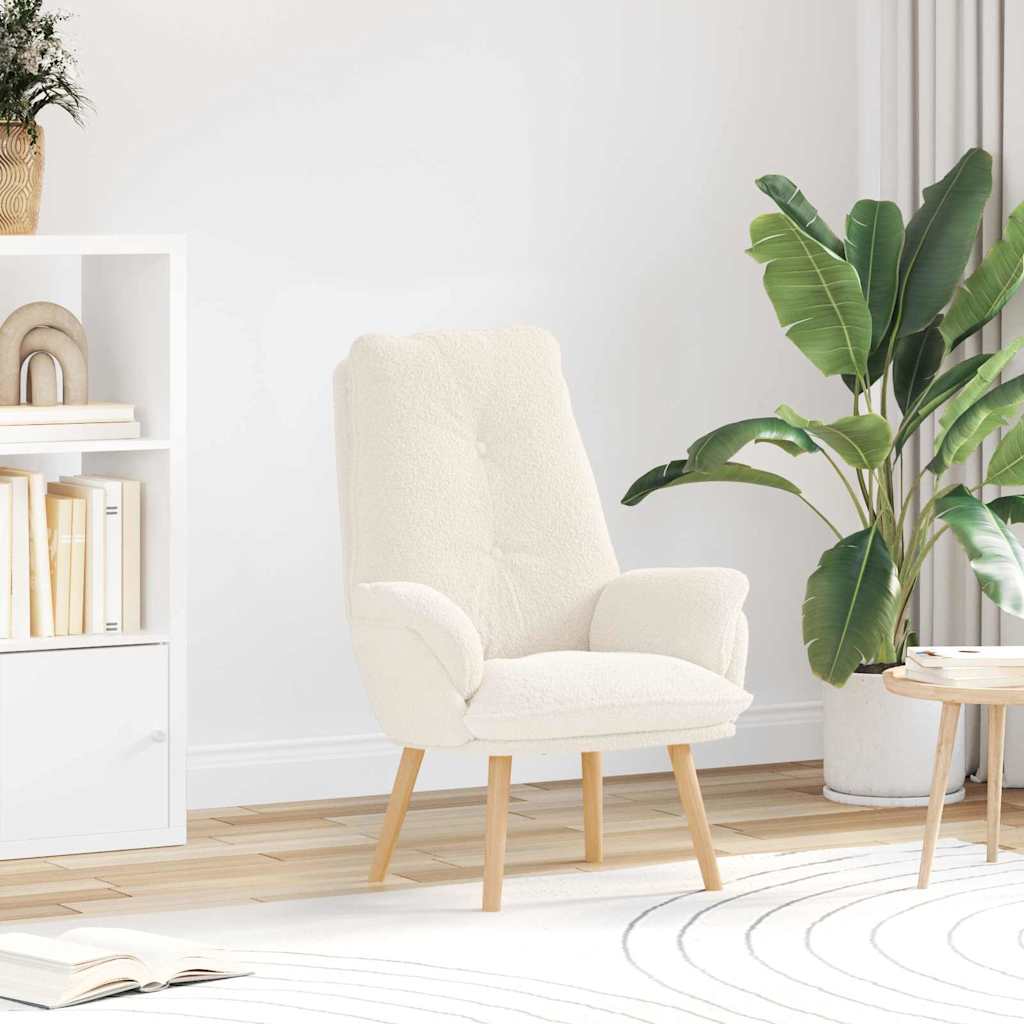 Poltrona branca de tecido felpudo com pernas de madeira em sala com estante, planta e mesa de madeira.