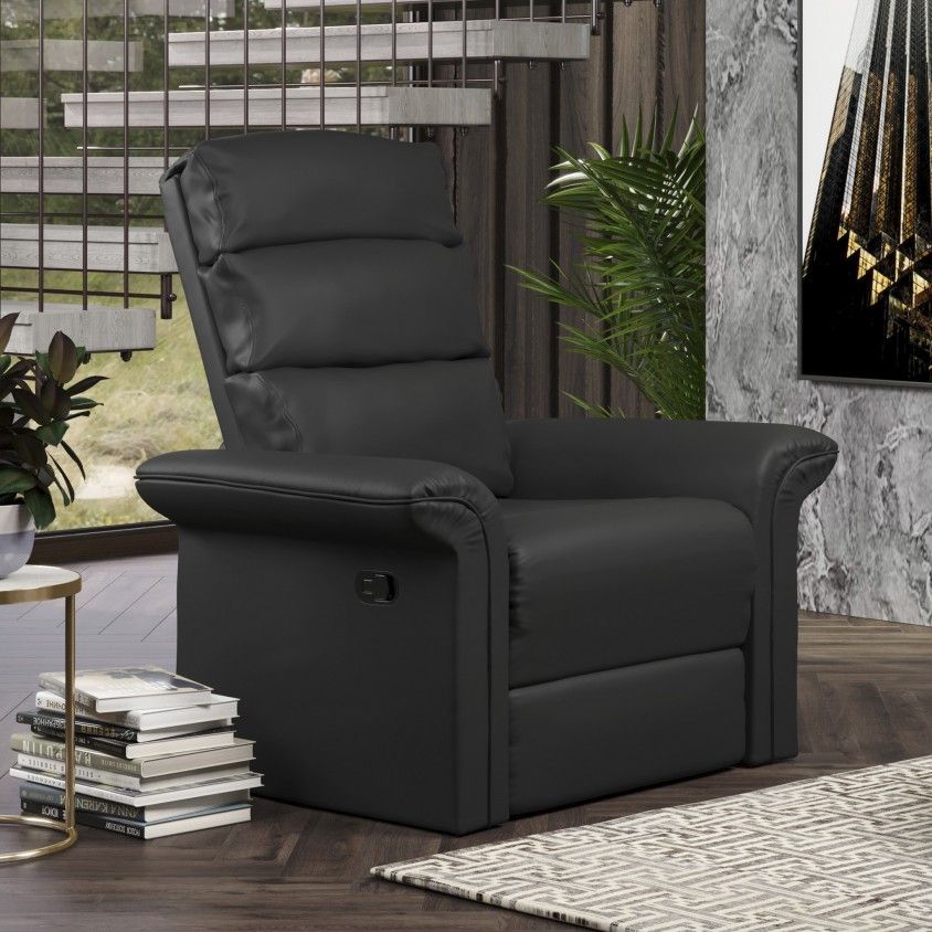 Poltrona preta em couro com controle elétrico junto a mesa com livros e plantas