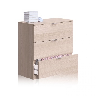 Cômoda de madeira clara com três gavetas e toalhas brancas em cima