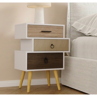 Aparador de madeira e branco com três gavetas e pernas amarelas ao lado de cama