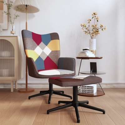 Cadeira patchwork colorida com base preta e apoio para pés, ao lado de mesa redonda e luminária de piso