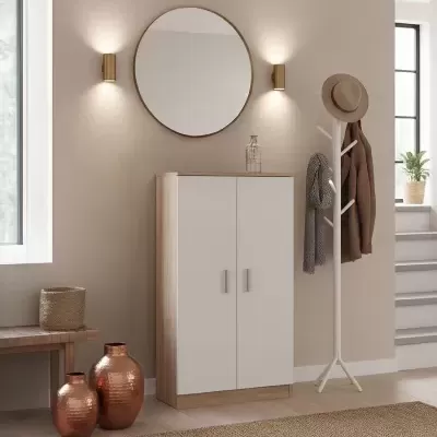 Móvel de arrumação branco com madeira clara, espelho redondo dourado, candeeiros, cabide com roupa e vasos metálicos num ambiente interior