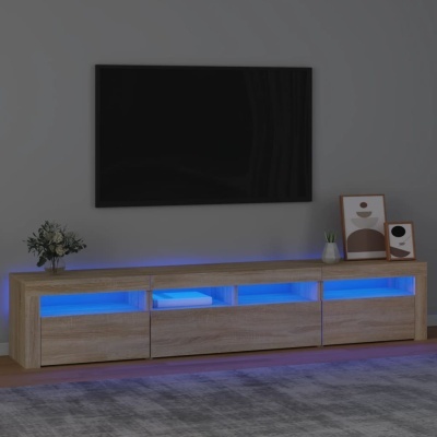 Móvel TV madeira clara com luz azul, TV preta na parede, plantas e quadros decorativos.