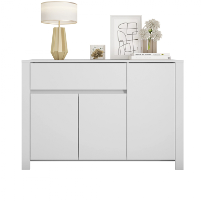 Aparador branco com gaveta e portas, lâmpada, quadro, flores e livros em cima.