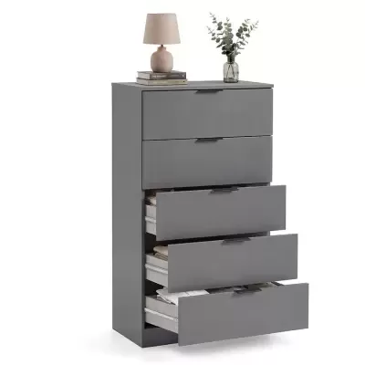 Cómoda cinzenta com gavetas abertas, lâmpada, livros e vaso decorativo no topo.