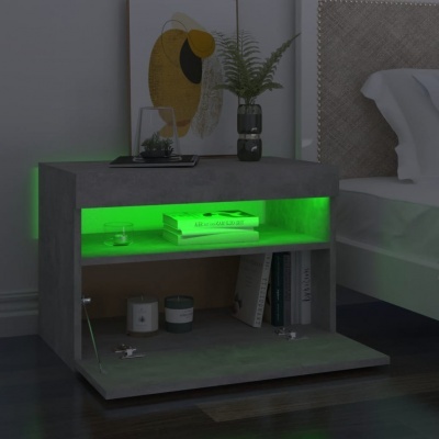 Mesa de cabeceira cinzenta com luz LED verde e objetos como livros, planta e velas ao lado de cama