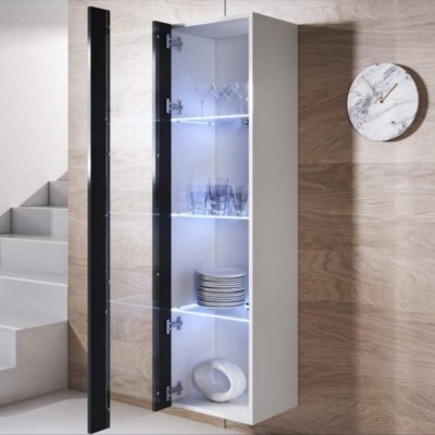 Armário de parede branco com porta de vidro preta e prateleiras iluminadas, copos e pratos visíveis, parede de madeira clara e relógio redondo de mármore